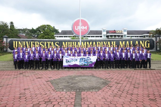 Large group of students in purple blazers on campus steps in front of Muhammadiyah Malang sign holding a Go to Campus banner.