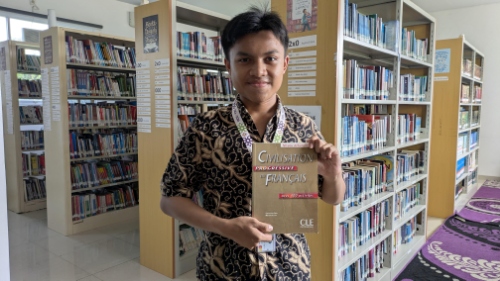 Young person standing in a library aisle holding a French textbook titled "Civilisation française," bookshelves filled with volumes in the background.