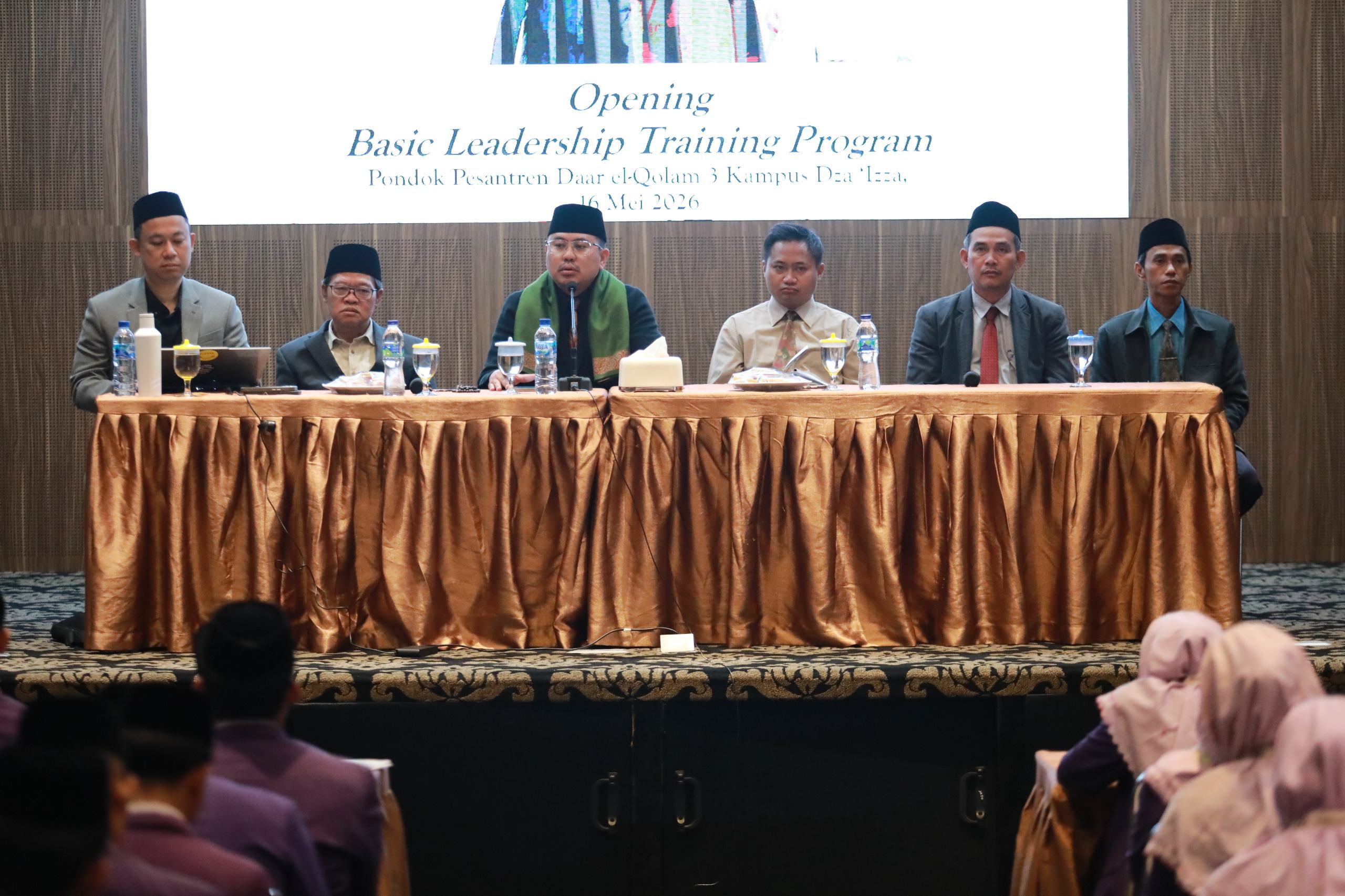 Six men wearing suits and songkoks seated behind a long table with a gold cloth at a leadership training panel.